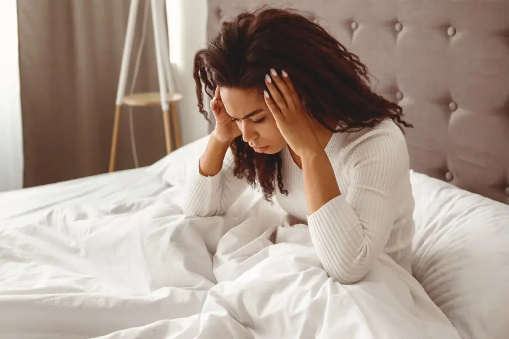 Black woman suffering from headache or migraine in bed