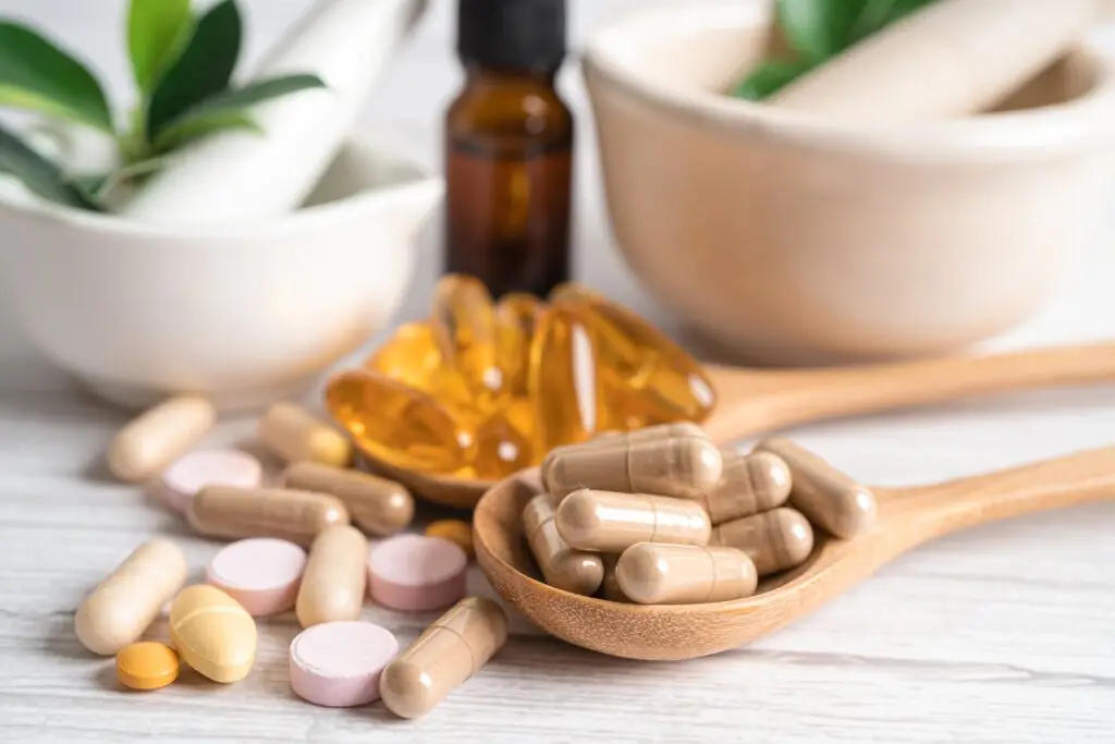 Various dietary supplements and pills on spoons.