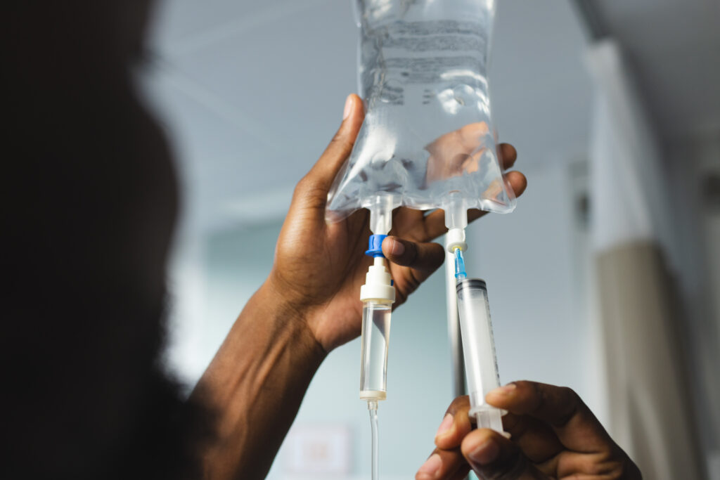Hands adjusting IV drip bag and syringe
