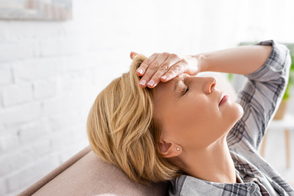 Woman with headache relaxing on couch
