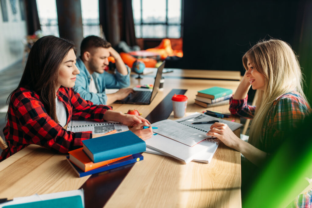 Students studying together at a wooden table.