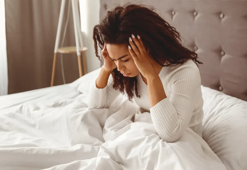 Black woman suffering from headache or migraine in bed