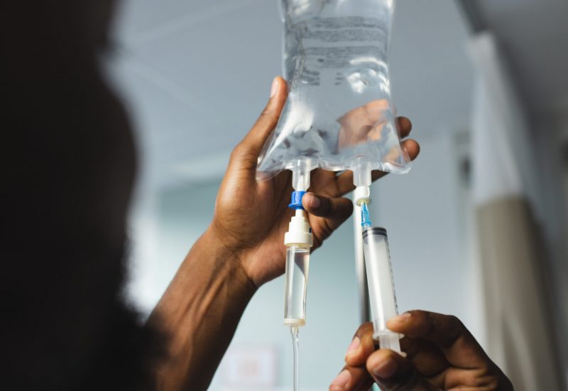Hands adjusting IV drip bag and syringe