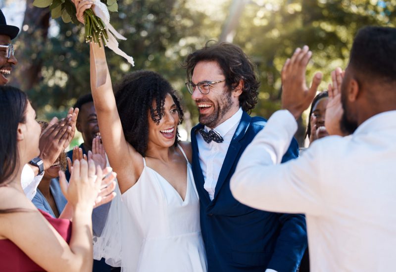 Happy couple celebrating wedding with friends outdoors.