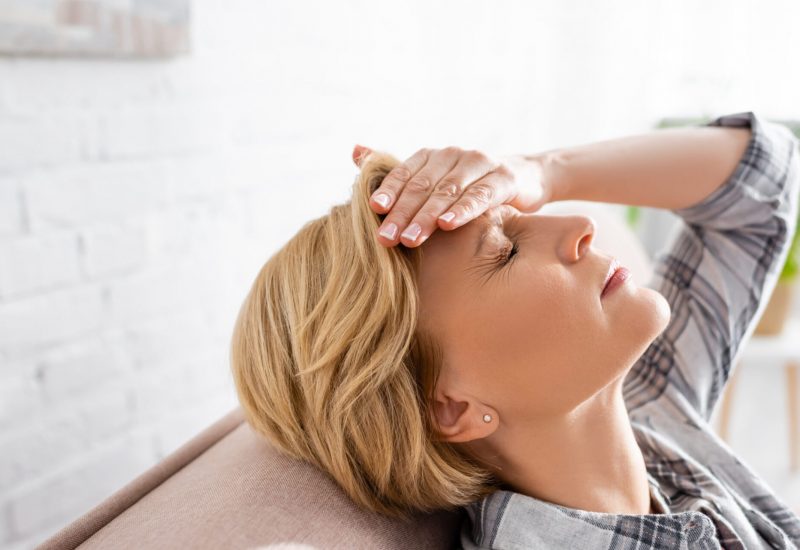 Woman with headache relaxing on couch